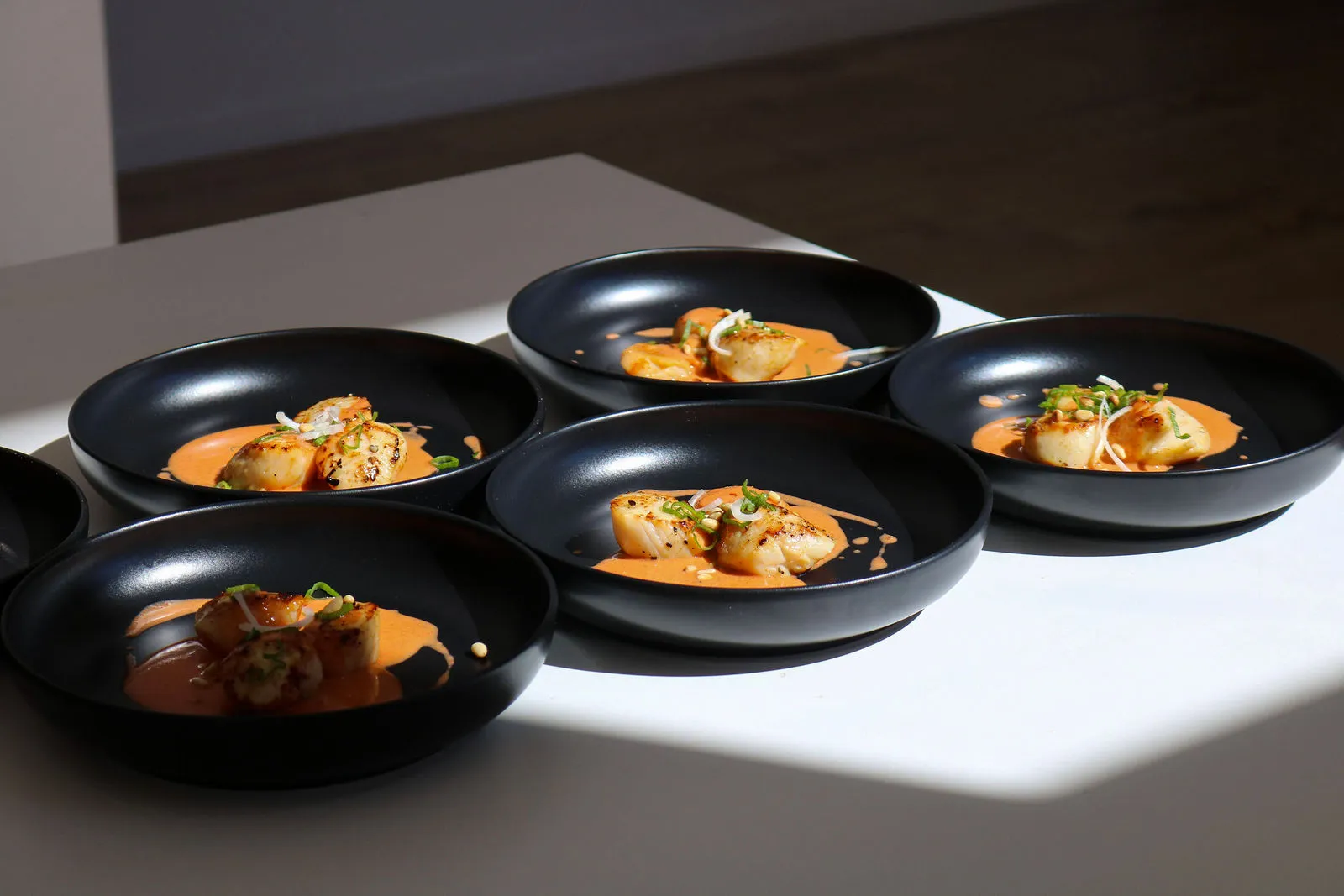Dressage gastronomique sur assiettes noires de Saint-Jacques par le Chef